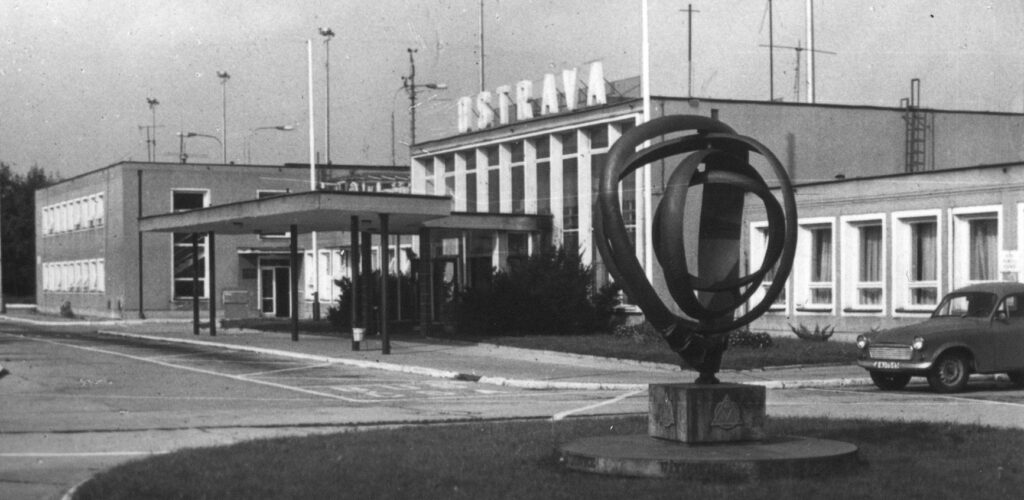 Historická černobílá fotografie staré odbavovací budovy letiště Ostrava se sochou před vchodem