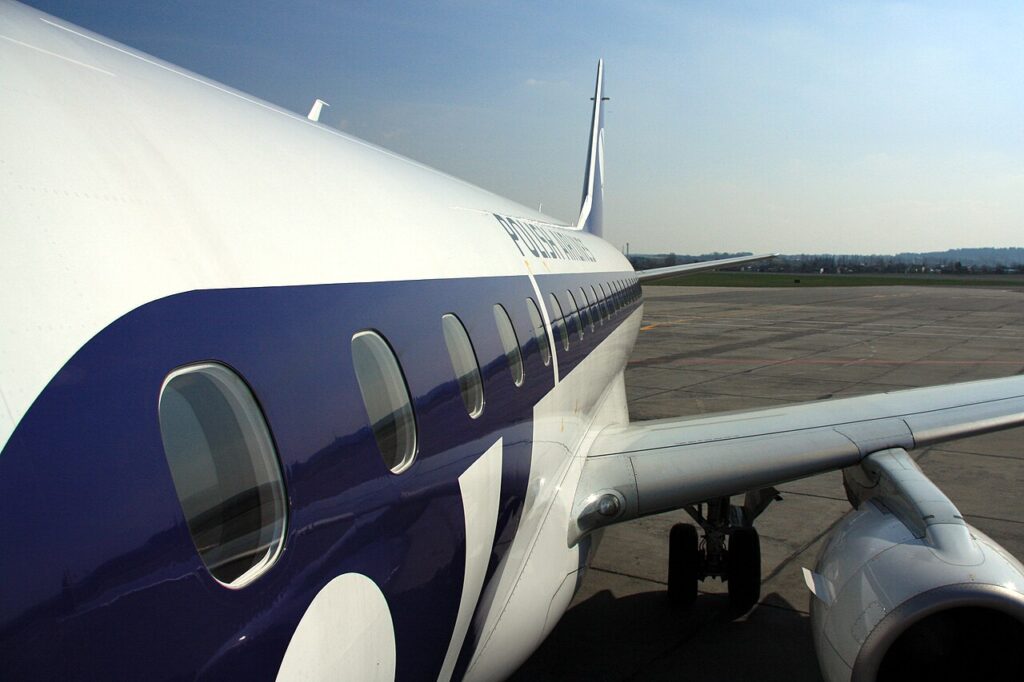 Bílý trup letadla Embraer s modrým pruhem a nápisem Polish Airlines na letištní ploše